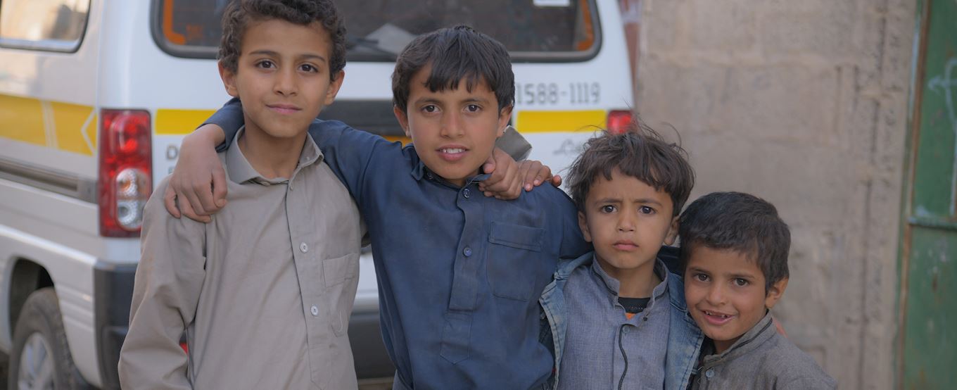 Four children standing in front of a car.